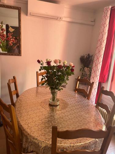 une table de salle à manger avec un vase de fleurs dessus dans l'établissement Gîte de la porte des Princes à Courthézon, à Courthézon