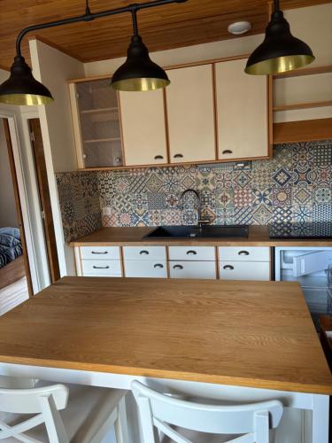 - une cuisine avec une table en bois et deux lumières dans l'établissement Le gîte de Lili, à Payrignac