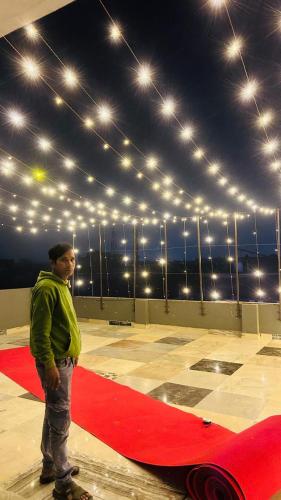 カーンプルにあるHotel JS INNの赤絨毯の横に立つ男