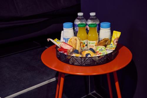 Una cesta de comida y bebidas sobre una mesa roja. en Love room évasion, en Tuchan