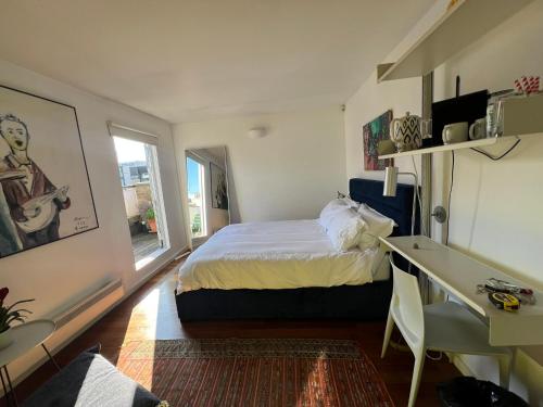 a bedroom with a bed and a desk and a window at Shoreditch Rooftop Suites in London