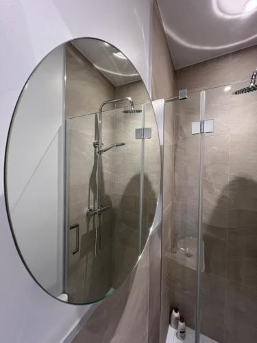a bathroom with a shower with a round mirror at Shoreditch Rooftop Suites in London