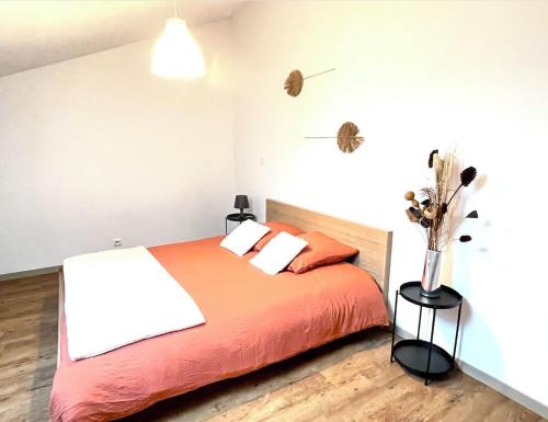 - une chambre dotée d'un lit avec des draps orange et un vase de fleurs dans l'établissement Le STAND' Gambetta, à Cholet