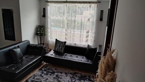 a living room with a black leather couch and a window at DESTINY Apto villas del Río in San Rafael