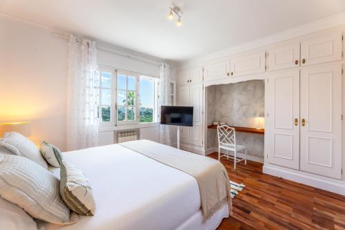 a white bedroom with a large bed and a tv at Aurora Boutique Hotel - Only Adults in Marbella