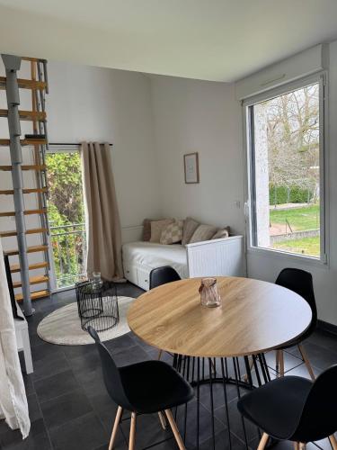 un salon avec une table, des chaises et un canapé dans l'établissement Petite maison cosy avec jardin, à Montceau-les-Mines