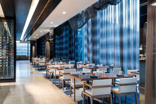 a dining room with tables and white chairs at Hilton Mexico City Santa Fe in Mexico City