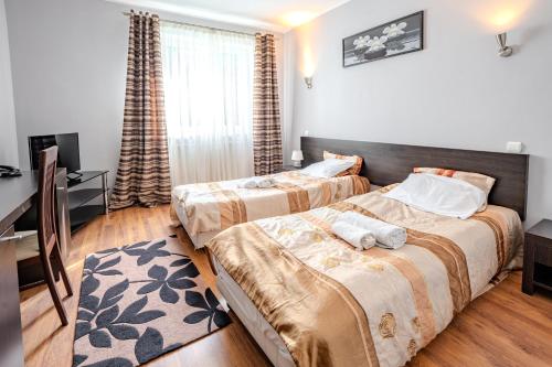 a bedroom with two beds and a desk and a television at Hotel Wiktoria in Wiązowna