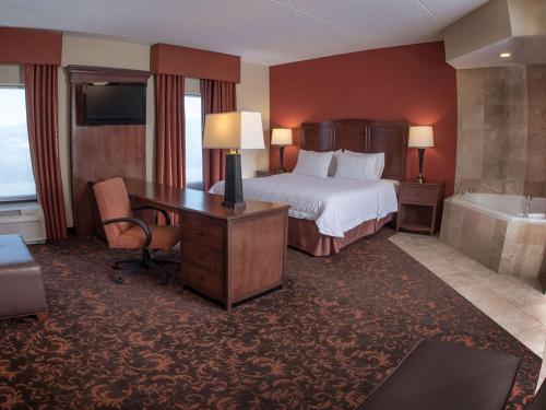 a hotel room with a bed and a desk and a tub at Hampton Inn and Suites Woodstock, Virginia in Woodstock