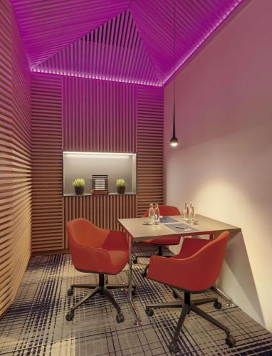 a dining room with a table and red chairs at Hilton Munich Airport in Oberding