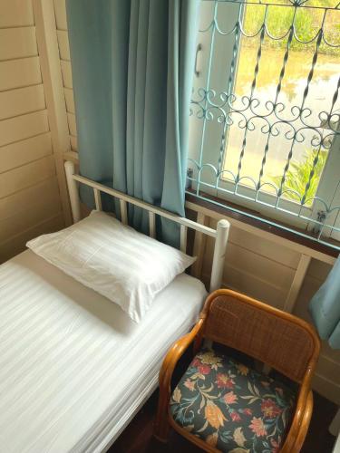 a small bed with a chair and a window at อยู่แพ PaeStay อุทัยธานี in Uthai Thani
