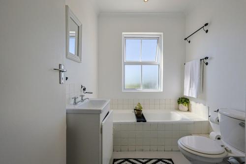 a white bathroom with a sink and a toilet at Fully Equipped Claremont Home with Pool & Style in Cape Town