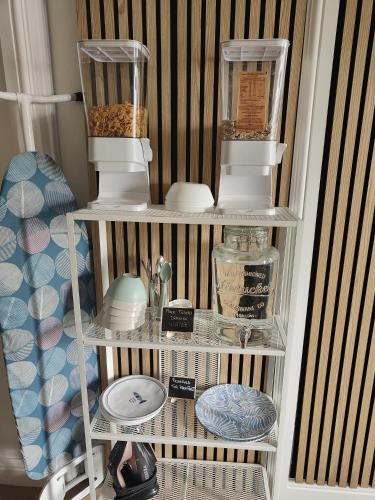 a shelf with dishes and other items on it at Clifton House O2 & Excel Rooms with private bathroom and Breakfast option in London