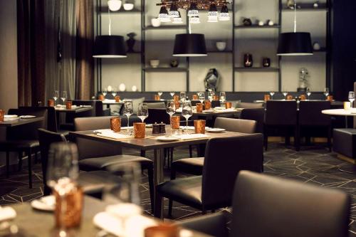 a dining room with tables and chairs and lights at Hilton Tallinn Park in Tallinn