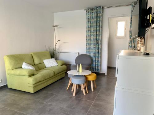 un soggiorno con un divano verde e un tavolo di Maison Le Jean Bart a Cap d'Agde
