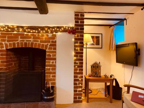 a living room with a brick fireplace with a television and a table at The Hill, Great Walsingham in Little Walsingham