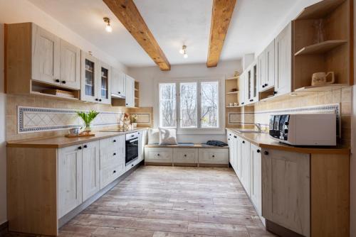 a kitchen with white cabinets and a large window at U Leknínu in Doksy