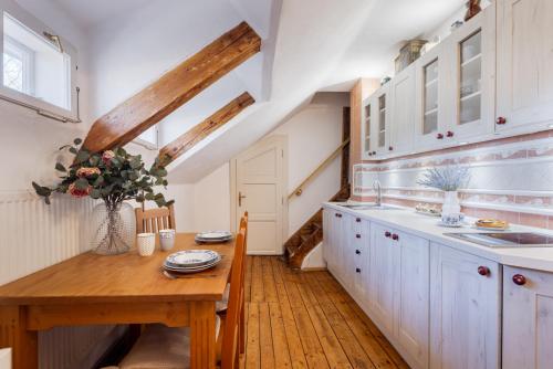 a kitchen with white cabinets and a wooden table at U Leknínu in Doksy