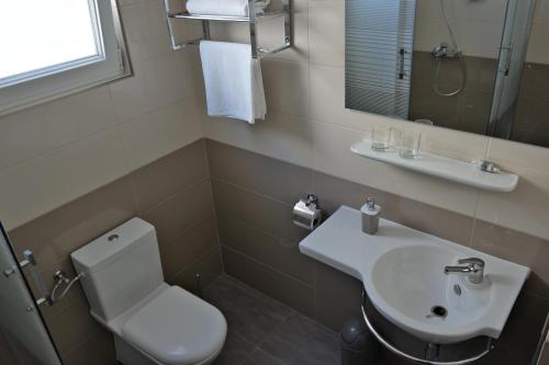 a bathroom with a white toilet and a sink at House Natali 70m from the beach - free EV top up in Rtina