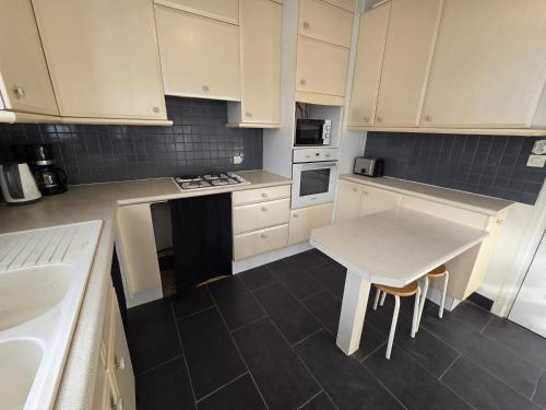 une cuisine avec des armoires blanches et une table à l'intérieur dans l'établissement Appartement spacieux en plein cœur de Brest, à Brest