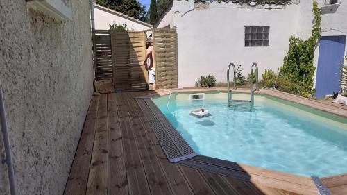 un homme debout à côté d'une piscine sur une terrasse en bois dans l'établissement Le Clos de Val, à Valréas