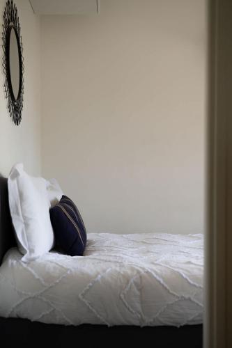 une chambre avec un lit avec des draps blancs et un miroir dans l'établissement Appartement moderne au coeur de Cannes, à Cannes