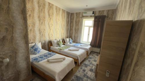 a room with three beds and a window at Alisher B&B Hotel in Samarkand