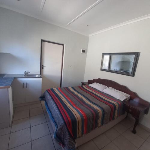 a small bedroom with a bed and a mirror at Overnight Lodge in Cape Town