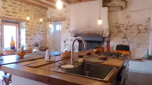 une cuisine avec un évier et une cuisinière four supérieur dans l'établissement Ti Rose, Maison de charme au port de Saint Cado, à Belz