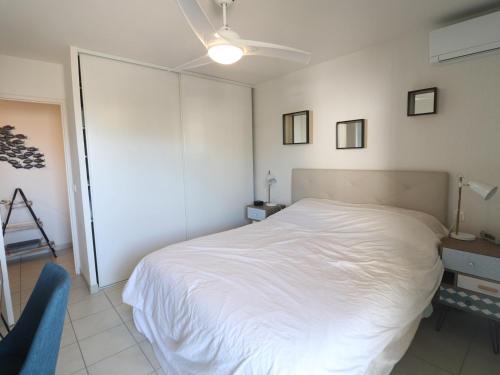 une chambre avec un lit blanc et une chaise bleue dans l'établissement Sète : Appt 2 Pièces, Climatisé, Résidence avec Piscine - FR-1-472-210, à Sète