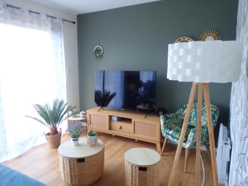 - un salon avec une télévision, une chaise et une table dans l'établissement Ria d'ETEL maison en bois ensoleillée à 150m de la plage, à Plouhinec