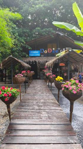 a wooden walkway with potted plants in front of a market at Do Dee cafe in Bangkok