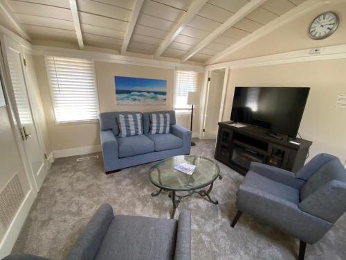 a living room with blue couches and a tv at Carmel Dolores Cottages in Carmel