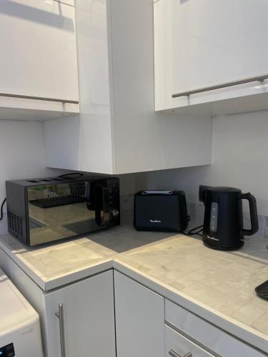 une cuisine avec des placards blancs et un four micro-ondes sur un comptoir dans l'établissement Cap d ail 2 pièces proches Monaco et plage, à Saint-Antoine