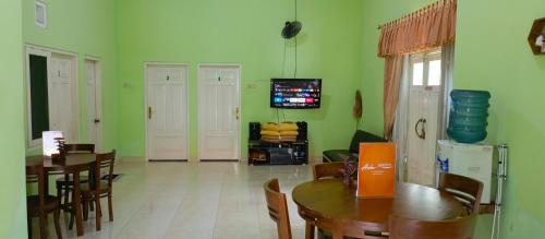 a living room with green walls and a table and chairs at Asoka Homestay Yogyakarta in Demangan