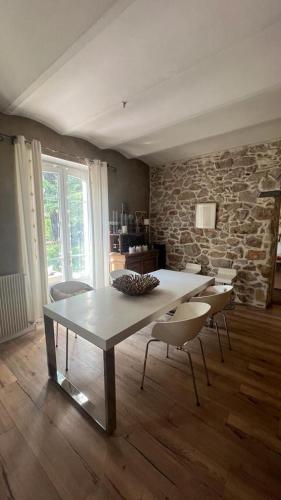 une table et des chaises dans une pièce avec un mur en pierre dans l'établissement Ales maison de ville tout confort piscine jardin parking 6 personnes, à Alès