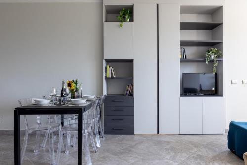 a dining room with a table and a tv at Elegant Seaside Apartment with Pool and Parking in Calambrone