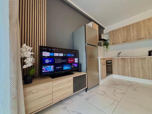 a kitchen with a flat screen tv on a wooden entertainment center at Steps to Sea - Affordable Luxury Living in St. Paul's Bay