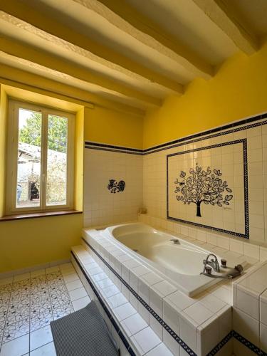 La grande salle de bains est pourvue d'une baignoire et d'une fenêtre. dans l'établissement Gîte Prestige avec Sauna, Spa, Piscine & Loisirs 15 pers, à Verteuil-dʼAgenais