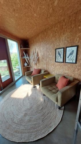 a living room with a couch and a large rug at Hut-Spot, comfortabel houten tuinhuis in Oud-Ade