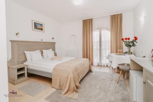 a white bedroom with a bed and a table at Veranda Panzio in Remetea