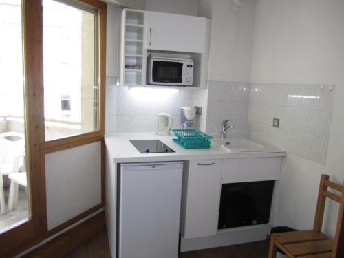 une cuisine blanche avec un évier et un micro-ondes dans l'établissement Studio Centre Brides-les-Bains : Balcon, Wi-Fi, Parking, Proche Télécabine & Thermes - FR-1-512-132, à Brides-les-Bains