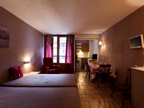 une chambre d'hôtel avec deux lits, une table et des chaises dans l'établissement Charmant studio pour 4 pers. avec balcon, parking et wifi, à deux pas des Thermes et du centre village - FR-1-512-212, à Brides-les-Bains