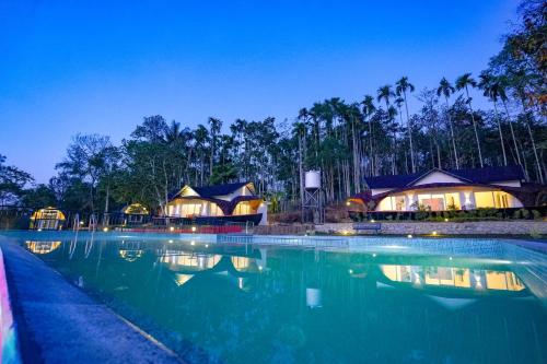 a swimming pool with some resorts in the background at Ginberry Holidays in Wayanad