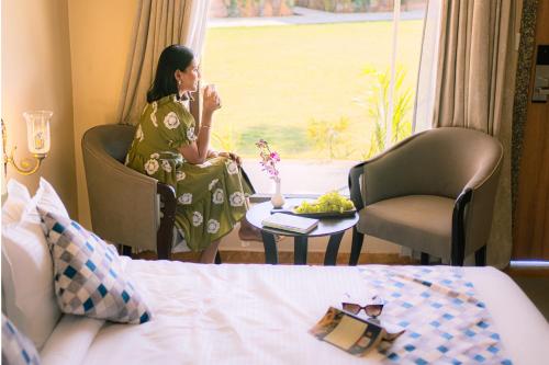 a woman sitting in a room looking out the window at Imperia Resort by The Sky Imperial, Nathdwara in Nāthdwāra