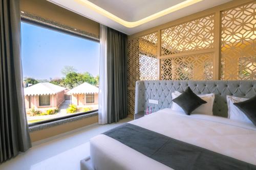 a bedroom with a bed and a large window at Imperia Resort by The Sky Imperial, Nathdwara in Nāthdwāra