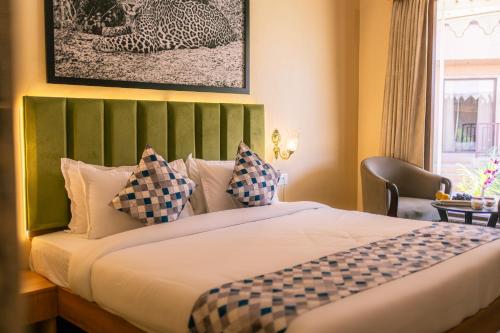 a bedroom with a bed with a green headboard and a window at Imperia Resort by The Sky Imperial, Nathdwara in Nāthdwāra