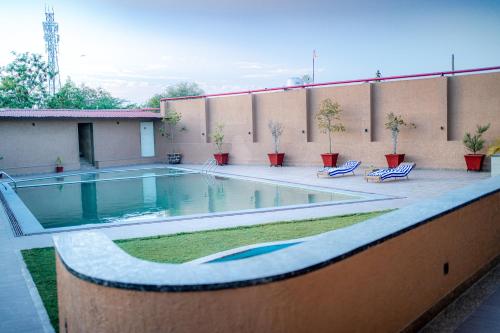 a swimming pool on a patio with two lounge chairs at Imperia Resort by The Sky Imperial, Nathdwara in Nāthdwāra