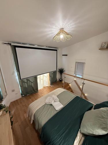 a bedroom with a large projection screen and a bed at Capstay hyper Centre Arras in Arras