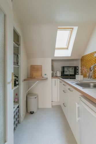 une cuisine avec des armoires blanches et une fenêtre dans l'établissement Résidence du Steir - T2, à Quimper